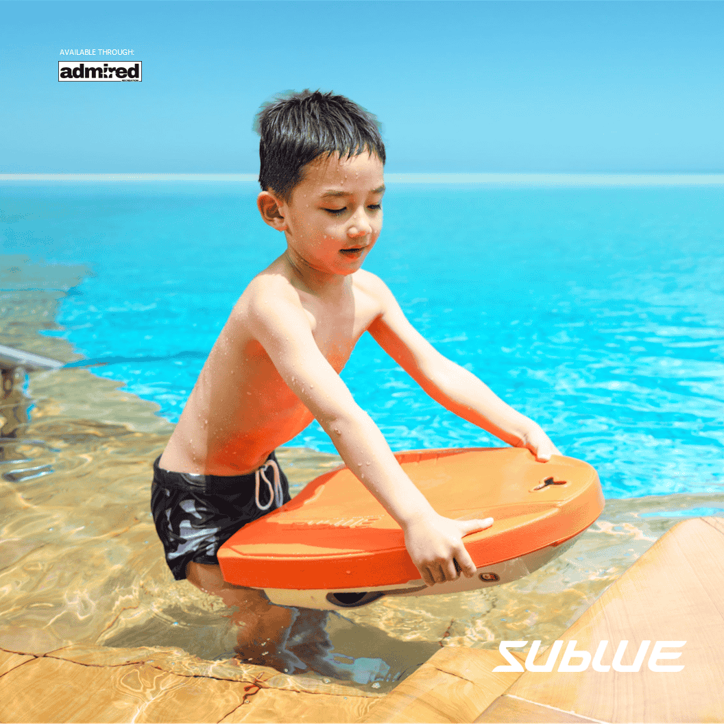 Boy holding orange SUBLUE Swii Electronic Kickboard at poolside, ready for fun.