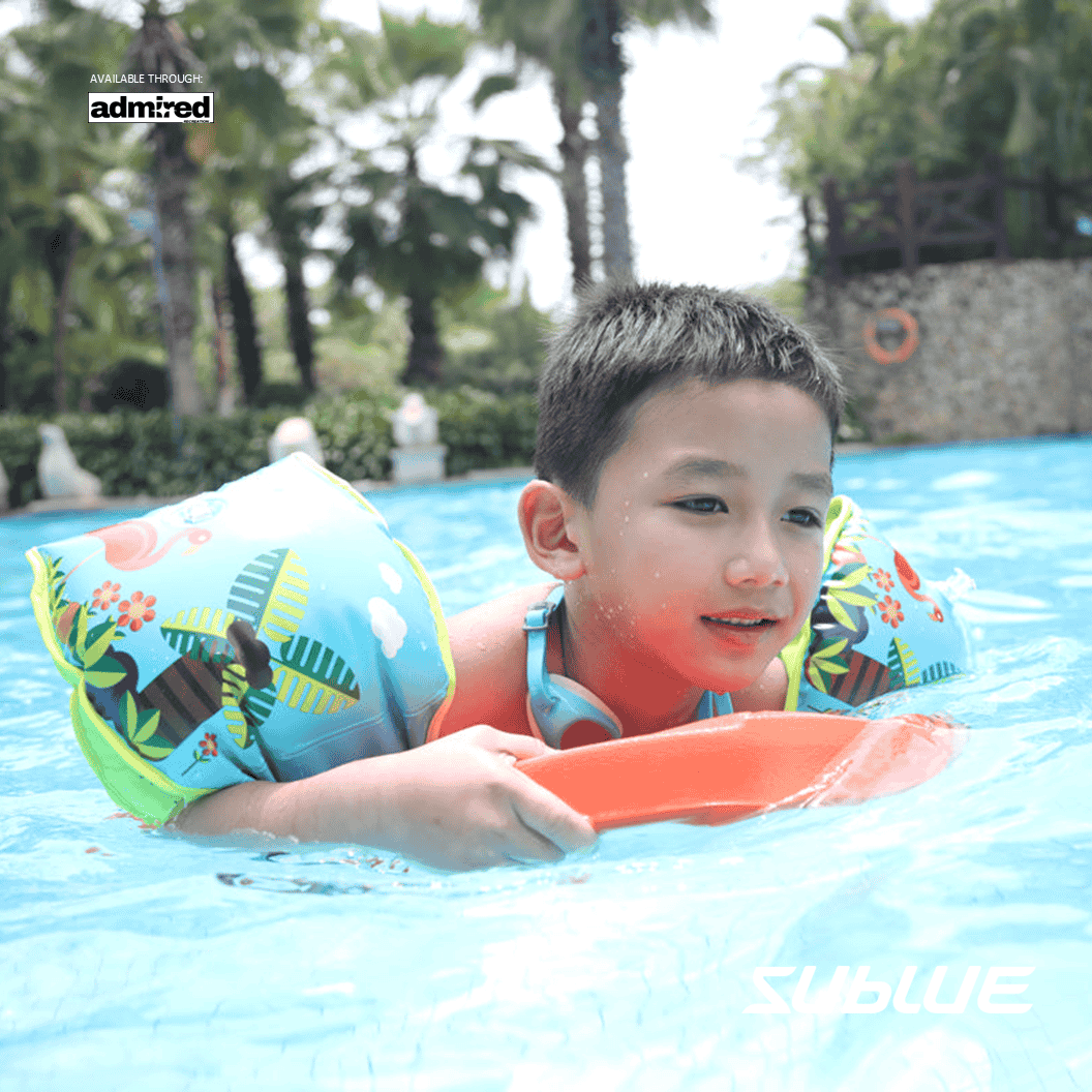 Child enjoying swimming in a blue pool with colorful arm floaties.