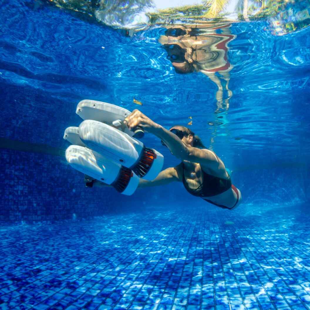 A female swimming underwater in a pool with Sublue Tini with Floaters